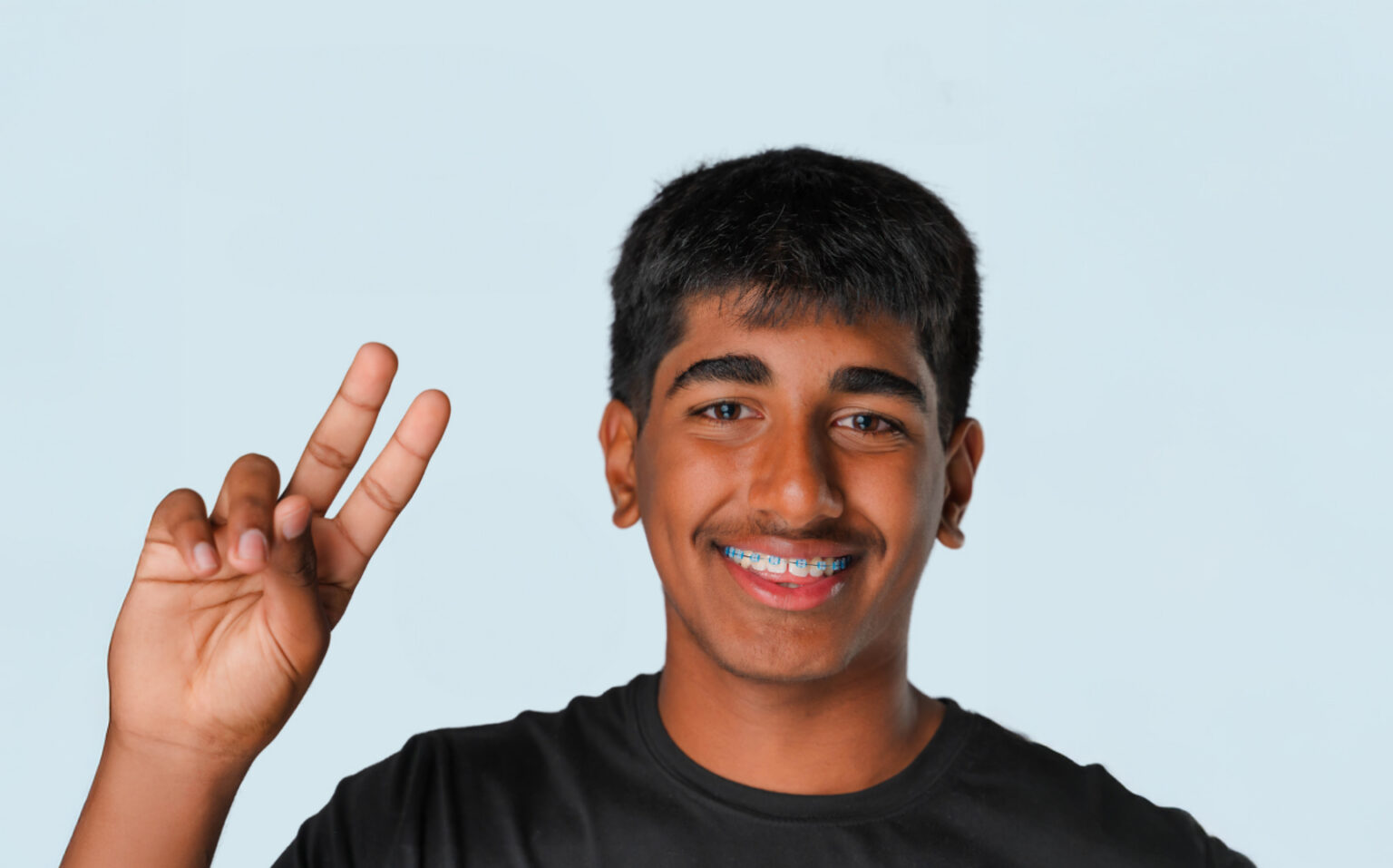 Young Man With Braces Giving The Peace Sign